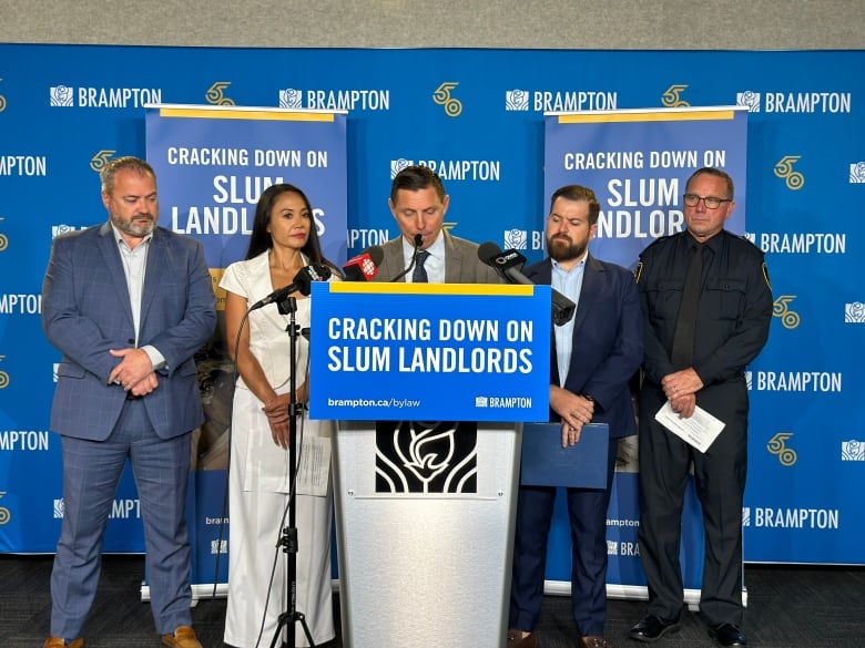 Five people standing behind a podium 