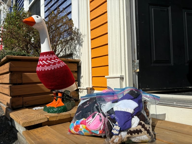 A goose statue stands next to plastic bags filled with small costumes.