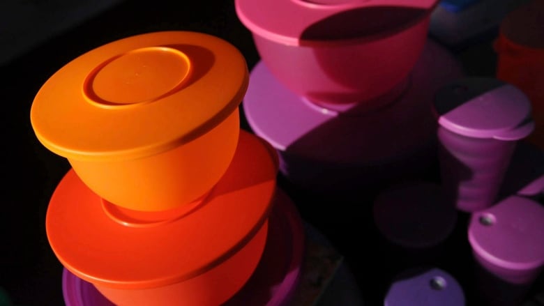 Stacks of rainbow Tupperware sit in a beam of sunlight.