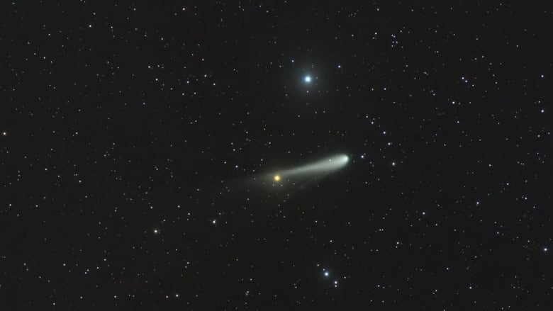 A bright object with a tail is seen in amongst many stars.