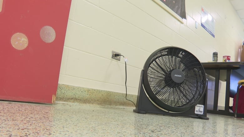 Black fan on a tile floor.