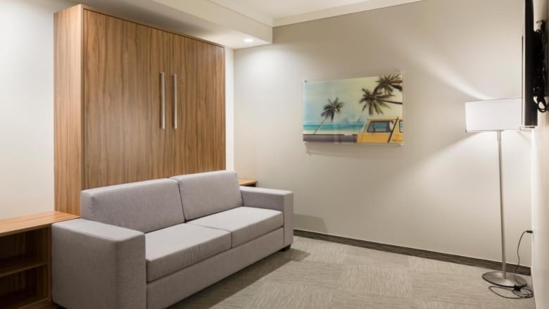 A couch shown in front of what looks like to be a closet door in a hotel room. 