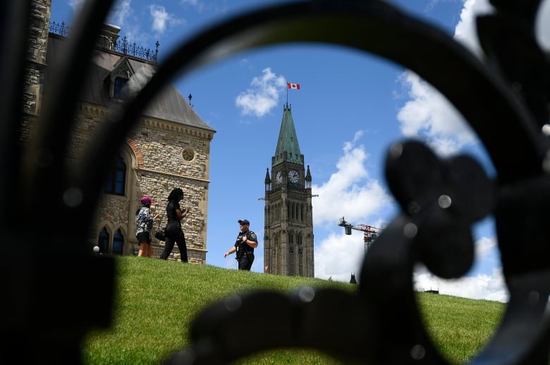 Centre Blocks Peace Tower is seen behind as a Parliamentary Protective Services officer walks on Parliament Hill in Ottawa.