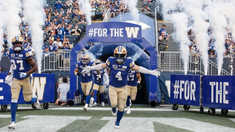 Man on a football uniform runs with its arms open in the stadium.