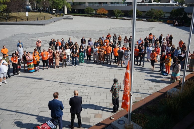 People in a circle formation around four flag poles.