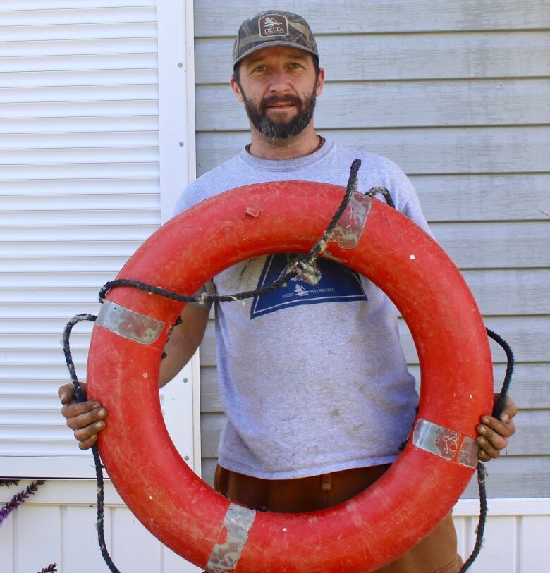 A man holds a large red life preserver.