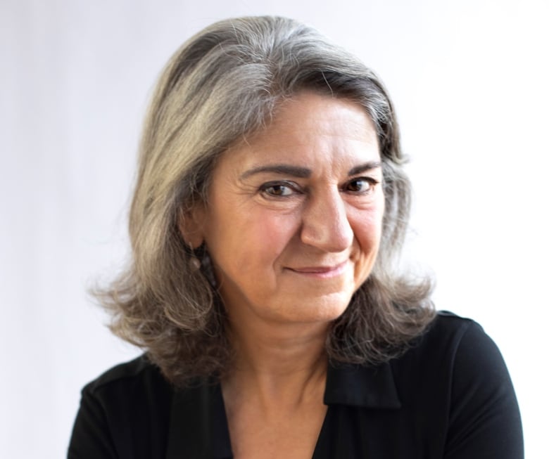 A woman in a black shirt wears a slight smile while posing for a portrait.