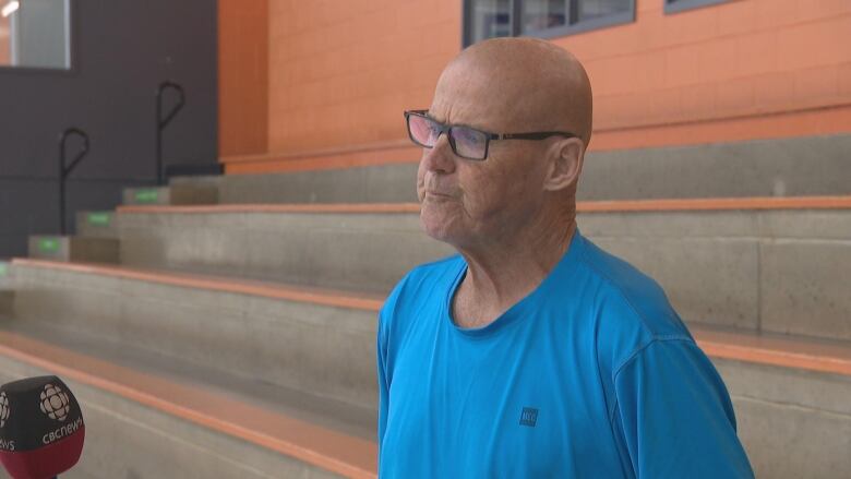 Bald man stands in hockey rink.