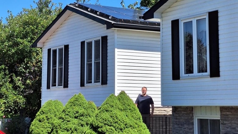 Man in front of semi-detached homes, one with solar panels