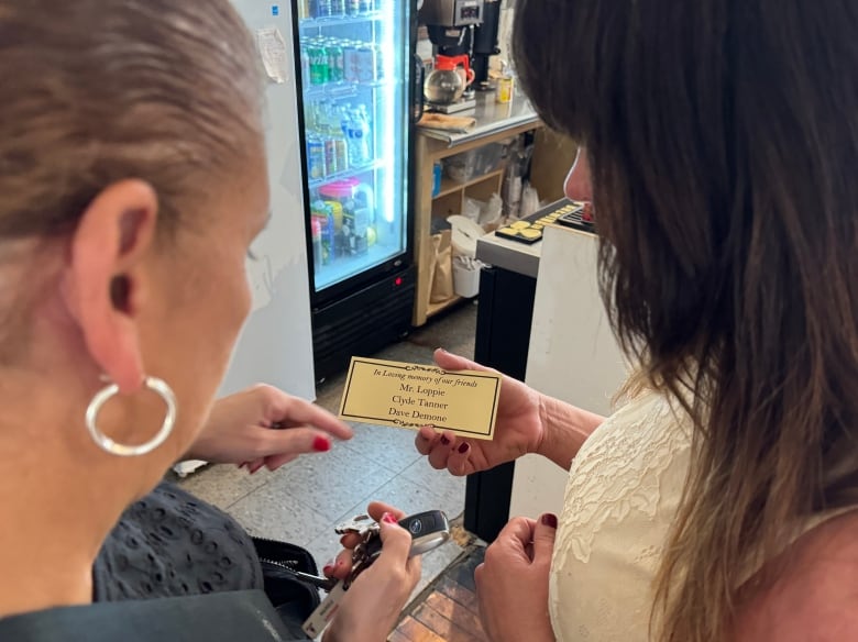 Woman holds brass rectangle with names on it.