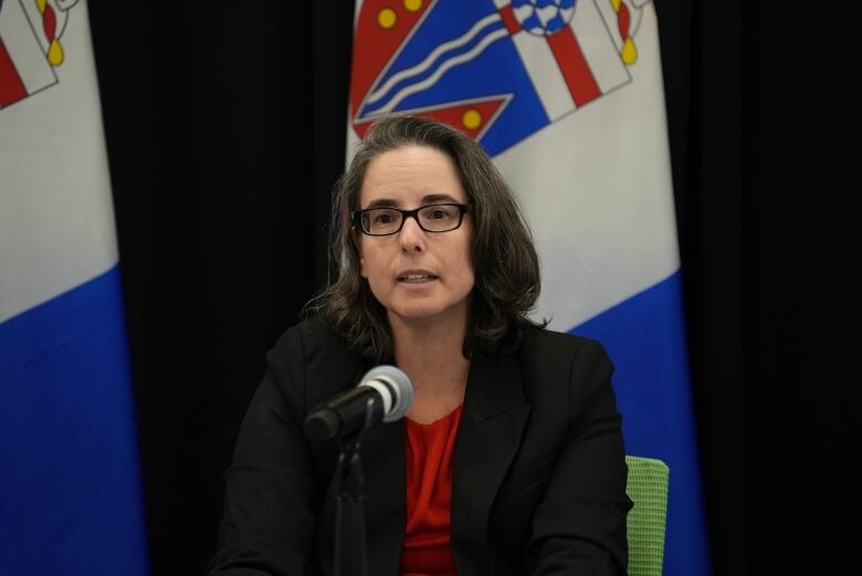 A woman in glasses speaks at a microphone.