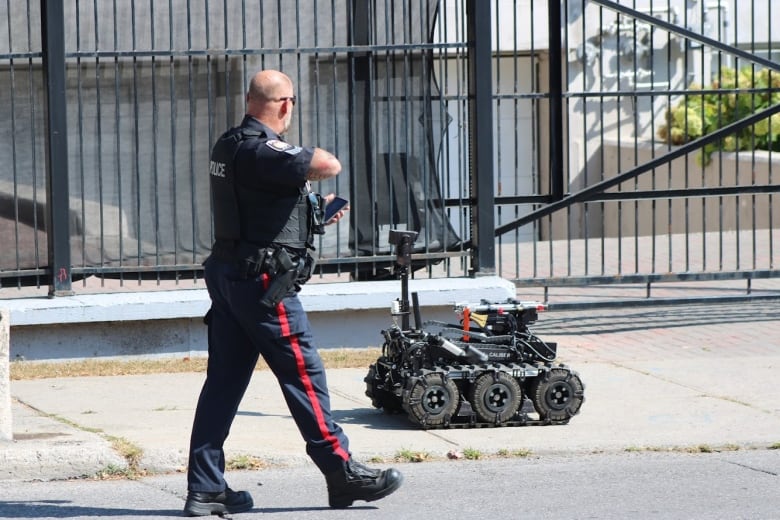 A police officer and a bomb disposal robot.