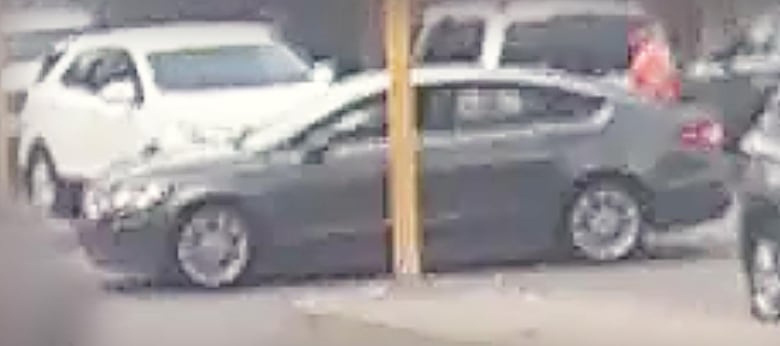 A fuzzy image of a grey car in a parking lot.