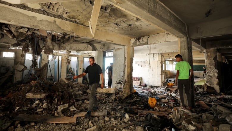 Palestinians inspect a building destroyed in an airstrike.