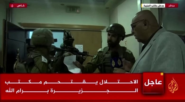 A screen grab from video shows a man reading a piece of paper held up by a soldier, as other soldiers look on.