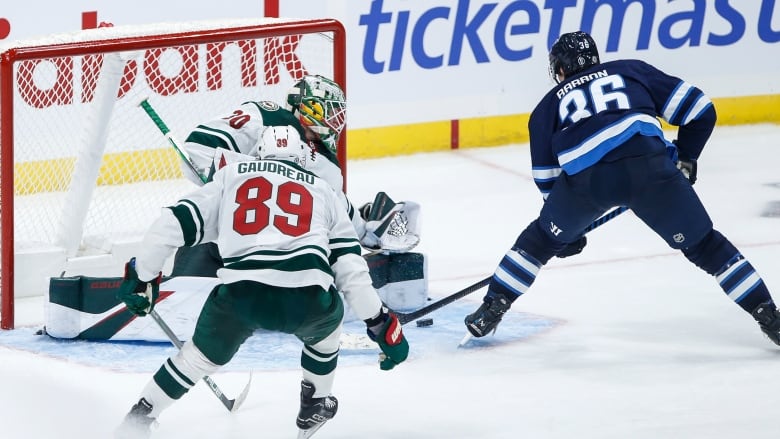 A hockey goalie saves the shot of another player on the opposing team. 