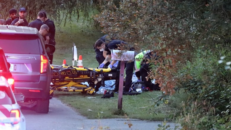 Emergency responders attend to what appears to be people on the ground, with a gurney visible.