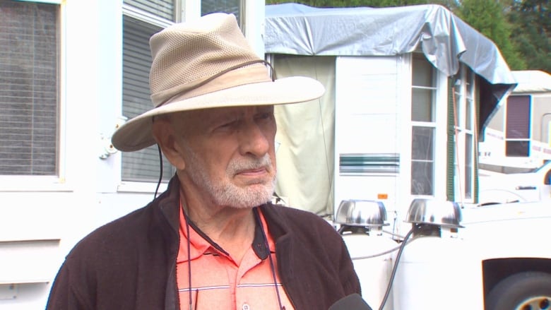 An older white man speaks while RVs sit in the background.