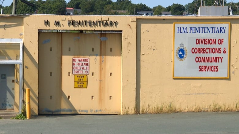 Yellow concrete wall with large door that says H.M. Penitentiary