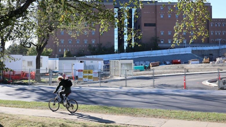 A cyclist passes by a hospital construction area.