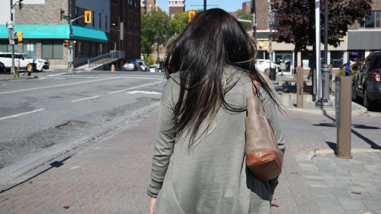 A woman walking on the street, picture was taken from behind so the face remains hidden.