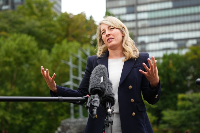 A woman gestures with her hands as she speaks into a microphone.