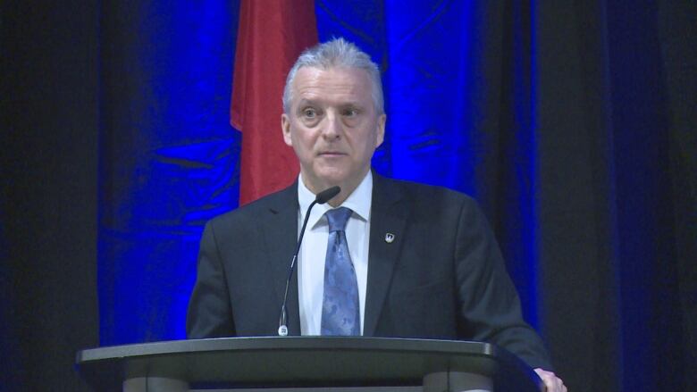 A man in a suit at a podium.