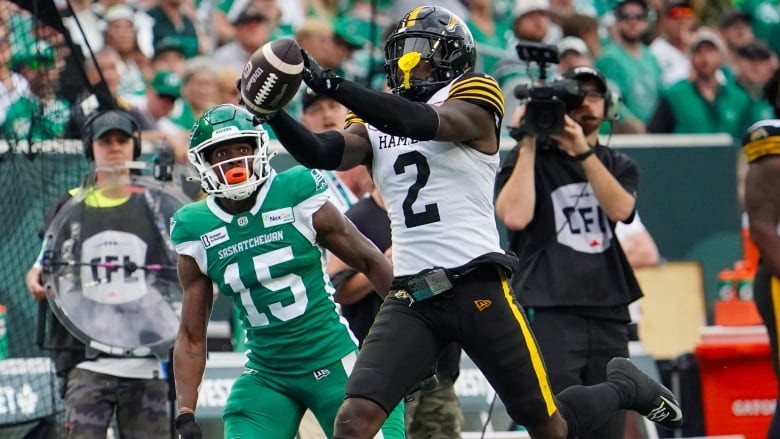 Hamilton Tiger-Cats defensive back Jamal Peters (2) intercepts the football as Saskatchewan Roughriders receiver Shawn Bane Jr. (15) looks on during the first half of CFL football action in Regina, on Sunday, June 23, 2024. 