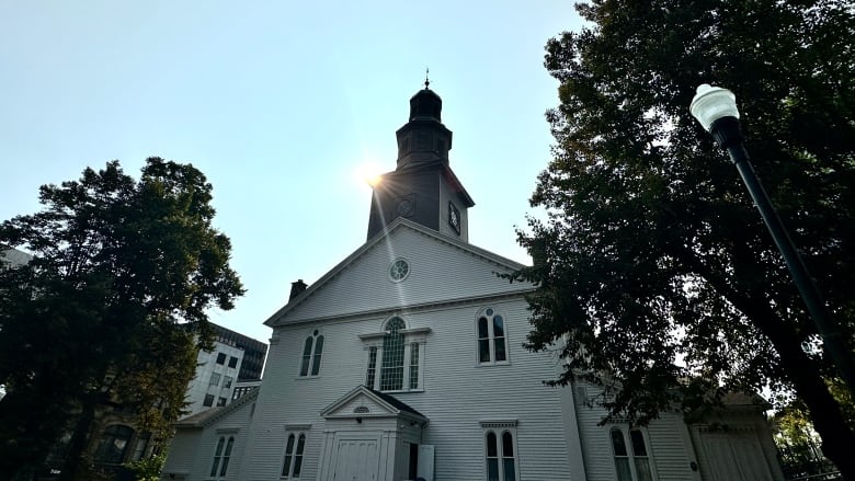 A white chuch with a black steeple.