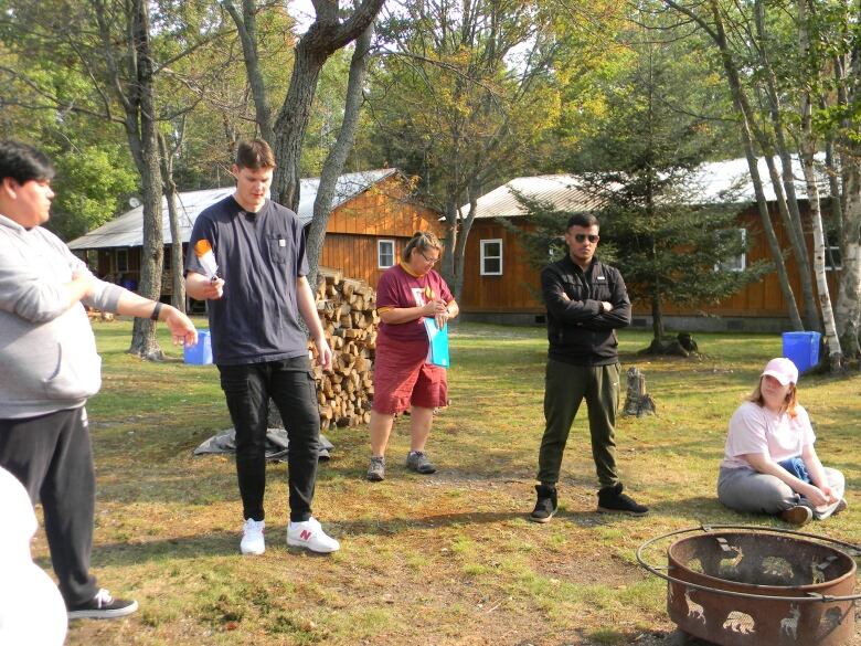 People standing near a fire pit at a camp.