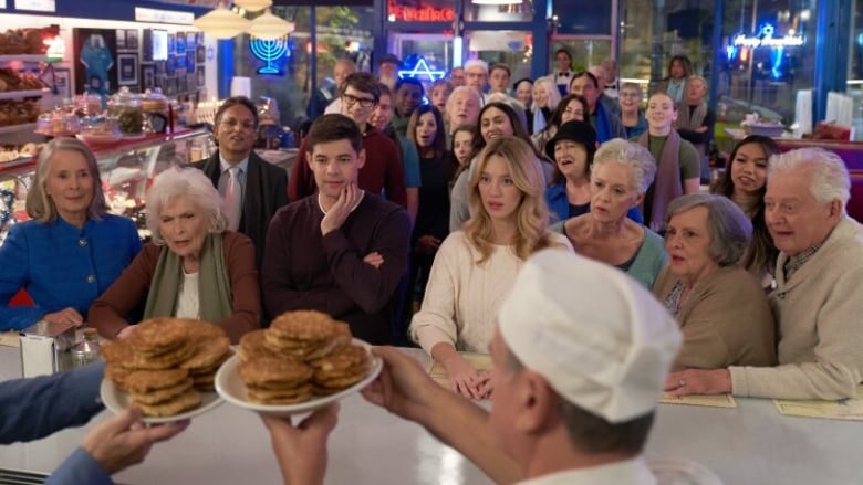 A still from a movie shows a large crowd of people gathered in a restaurant.