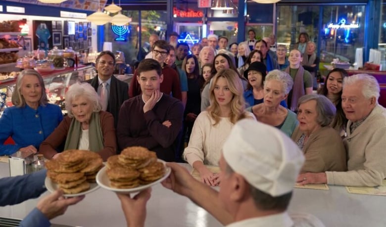 A still from a movie shows a large crowd of people gathered in a restaurant.