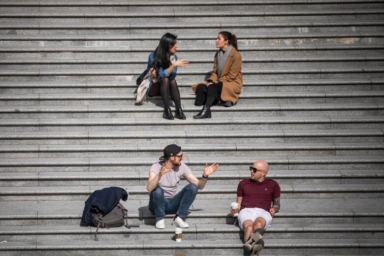 People are seen sitting and talking at Robson Square plaza in Vancouver.