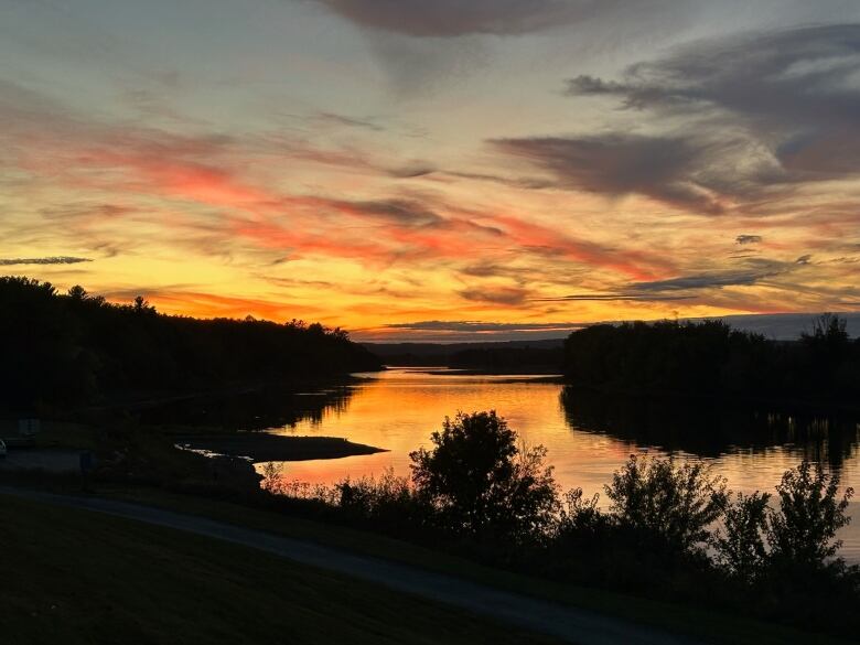 The sun sets over a river dotted by wooded islands.