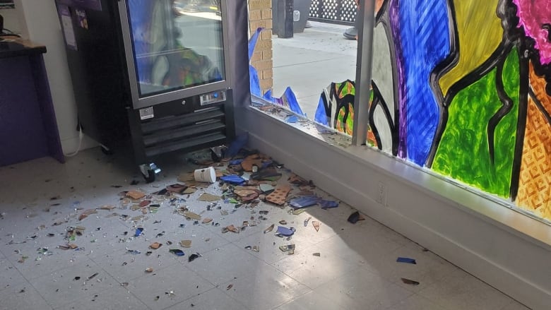 a broken glass front window in seen from inside of a shop 