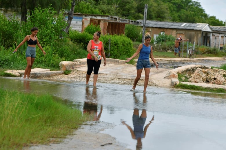 Three women walk in a flooded street