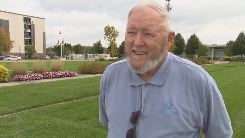 A man on a lawn with a building in the background.