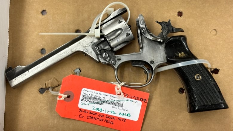 A revolver zip-tied to a box with an orange tag attached. 