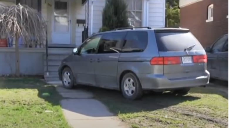 A minivan on a front yard.