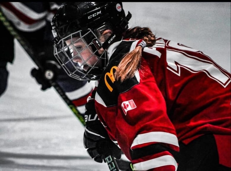 A young girl looks down at the ice waiting for the puck to drop in a game of hockey