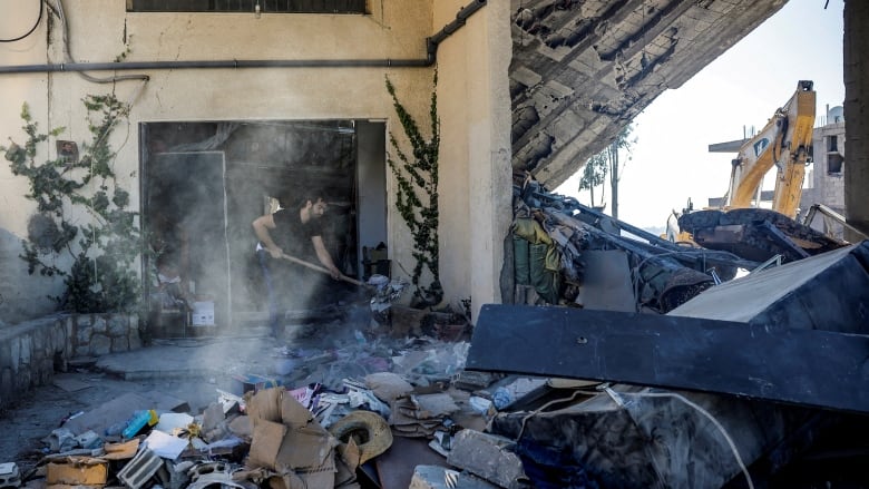 A man with a shovel moves debris as he searches for survivors after an airstrike hit a building.