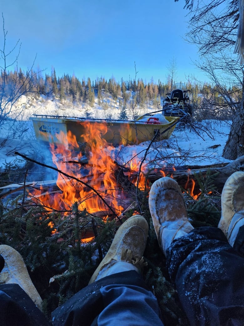 Two people's feet by a fire.