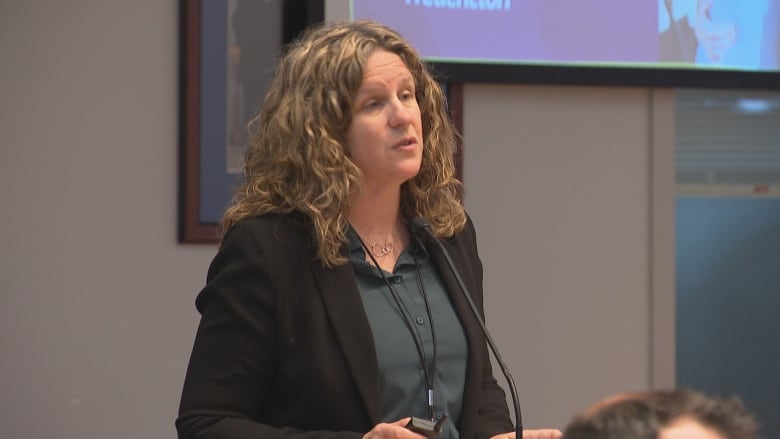 Stacey Russell speaks at a podium in Fredericton council chambers.