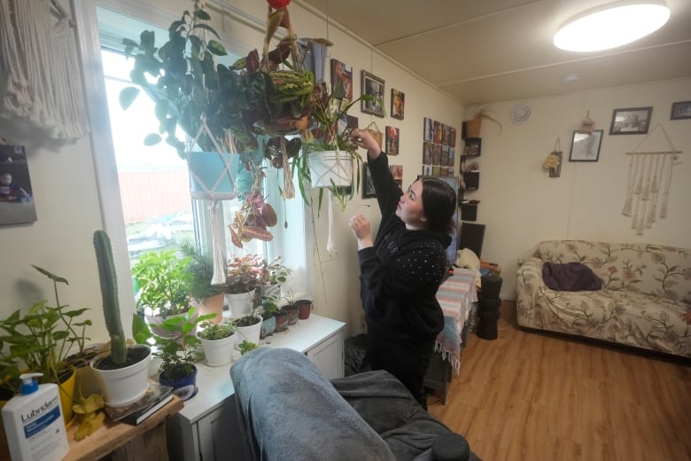 A woman waters plant in a home.