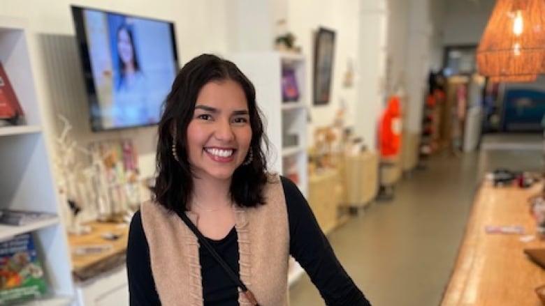 Woman in beige vest standing in store.