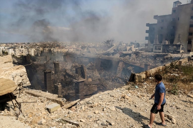 A person surveys a smoldering crater left by an airstrike.