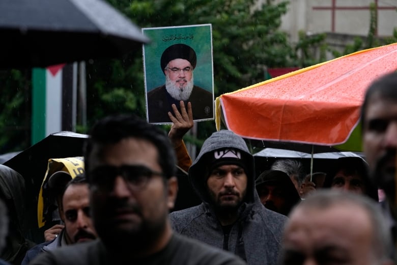 A person holds up a poster displaying a person's portrait during a demonstration.