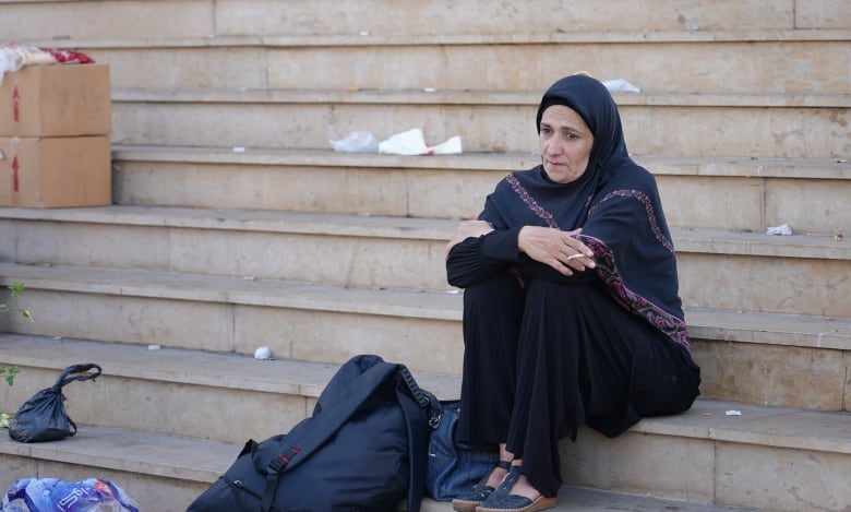 A woman sits on steps outside a mosque.