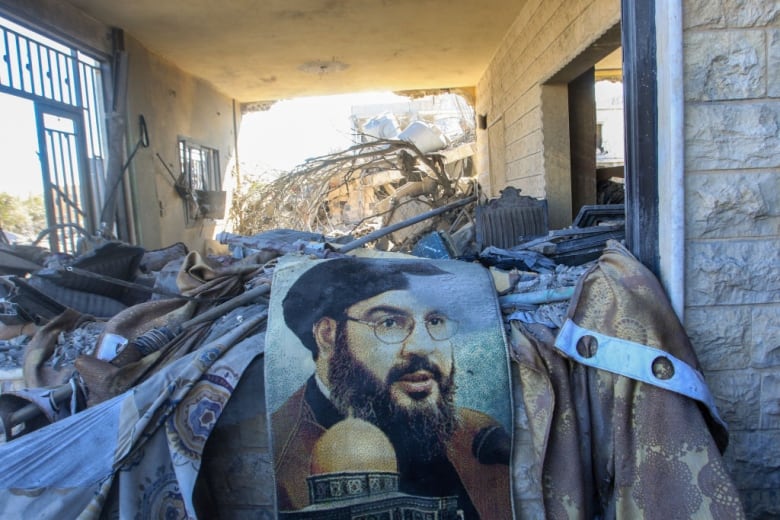 A portrait of Hezbollah chief Hassan Nasrallah sits amid destruction caused by an airstrike. 