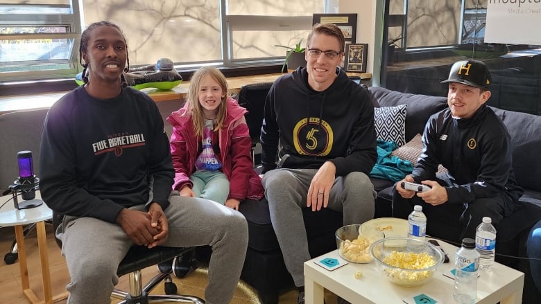 Four people sitting on a couch playing video games.